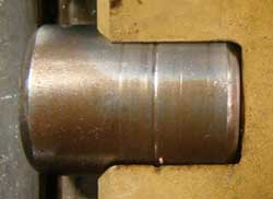 A groove worn into a cylindrical roller by a hard particle debris imbedded in the cage